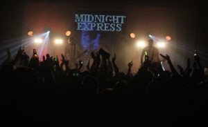 MEC Helbild 4 - Midnight express beskriver sig själva som en modern Elvis, ”Han skrev heller inga låtar men gjorde grymma versioner av andras musik som gjorde att människor inte kunde sitta stilla”. Midnight express repertoar innehåller allt från Avicii till Queen. De har levt på att spela musik i många år och spelar mycket av de senaste hitsen, men kan såklart alla gamla schlagers och hårdrockshits också. Full fart är mottot, bokar du Midnight express så får du garanterat ös på festen.